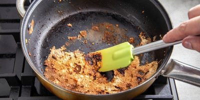 Pánev, na které je připeklé jídlo, které se snaží osoba dostat pryč stěrkou