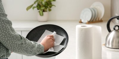 Osoba čistí v kuchyni pánev papírovou utěrkou