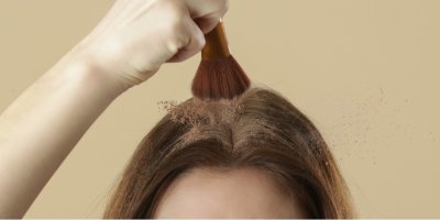 Žena, která si nanáší na vlasy suchý šampon