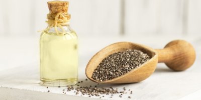 Chia semínka v dřevěné lopatce a olej z chia semínek