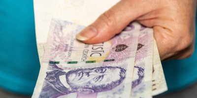 Ruka drží české bankovky