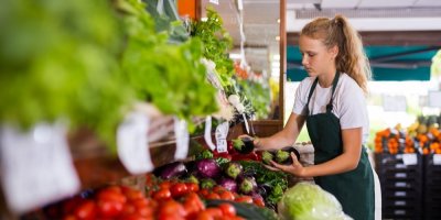 Mladá brigádnice pracuje v obchodě se zeleninou