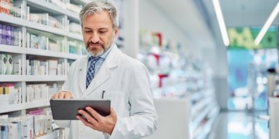 Starší lékárník kontroluje s pomocí tabletu léky v lékárně