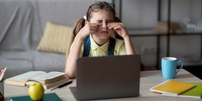 Mladá dívka sedící u počítače si mne oči