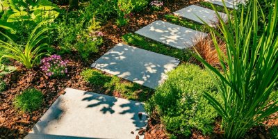 Detail zahradní cesty s kamennými deskami a mulčovací kůrou