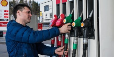 Muž na čerpací stanici drží palivovou trysku