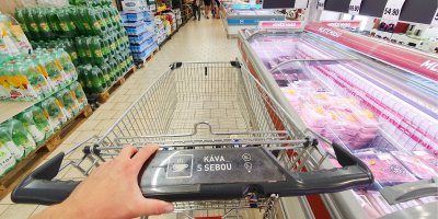 Člověk s nákupním vozíkem v uličce supermarketu