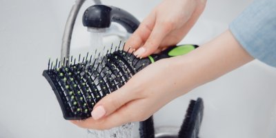 Žena umývá vlasový kartáč pod tekoucí vodou