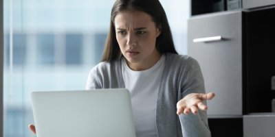 Mladá žena sedí u notebooku a řeší nějaký problém