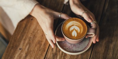 Žena uchopuje šálek kávy