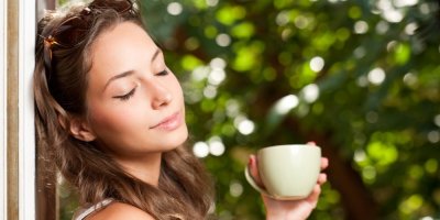 Žena se zavřenýma očima drží šálek