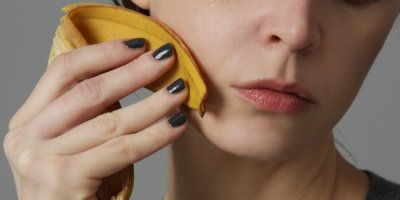 Mladá žena si potírá pleť banánovou slupkou