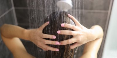 Žena si myje vlasy ve sprše