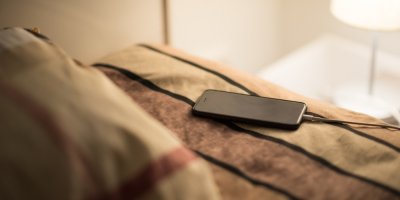 Telefon na posteli připojený k nabíječce