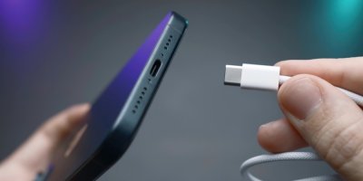 Člověk drží v rukou chytrý telefon a kabel s konektorem typu C 