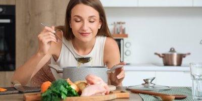 Žena ochutnáváme polévku z hrnce