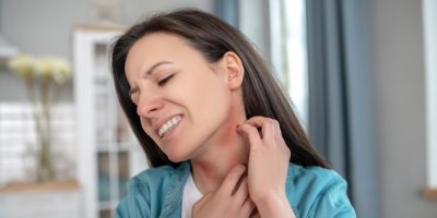 Žena si škrábe vyrážku na krku