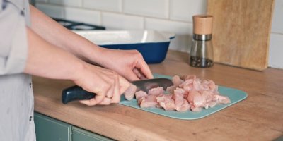 Žena v kuchyni krájí maso na kostičky