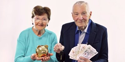 Dva senioři s bankovkami a prasátkem v rukou