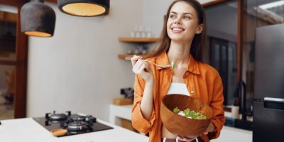 Mladá žena jí zeleninový pokrm z dřevěné mísy