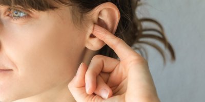 Žena si dává malíček do ucha