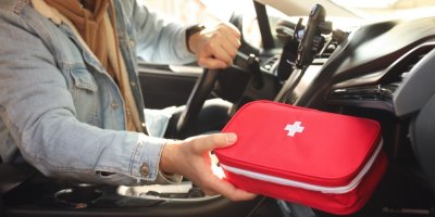 Muž v autě drží v ruce autolékárničku