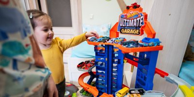 Holčička si hraje s autodráhou