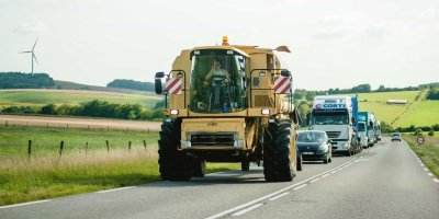 Silnice, po které jede traktor, auta a nákladní auta