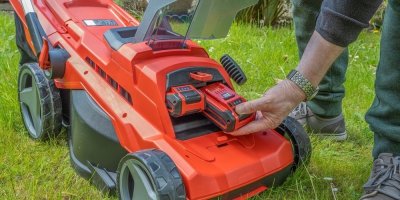 Muž vkládá akumulátor do slotu sekačky