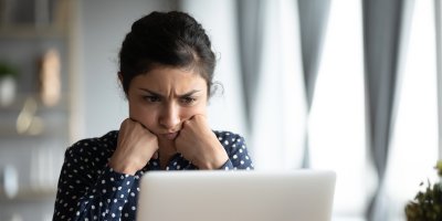 Žena sedí u notebooku a mračí se