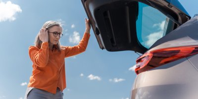 Starší žena otevírá kufr auta