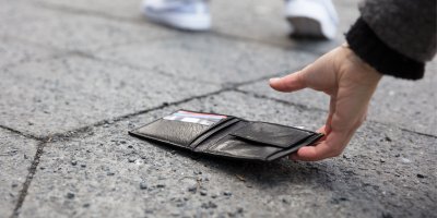 Ruka zvedá peněženku ze země