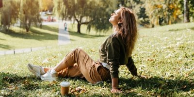 Mladá žena sedí na trávníku v parku a relaxuje