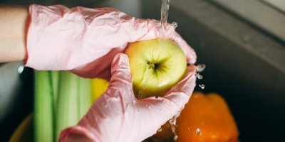 Žena umývá jablko pod tekoucí vodou