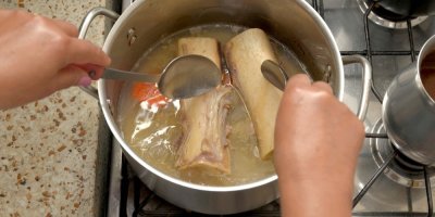 Žena vaří v hrnci vývar z kostí