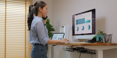 Žena pracuje ve stoje u stolu na počítači