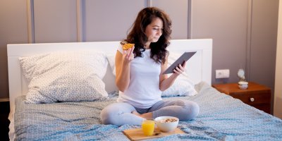 Žena sedí na posteli a jí