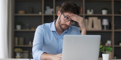 Muž sedí u notebooku a drží se za hlavu