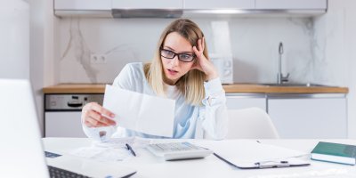 Žena sedí u stolu a drží v ruce formulář