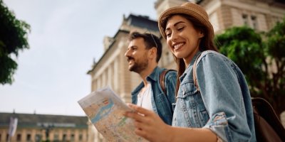 Žena a muž se prochází ulicemi a dívají se do mapy.