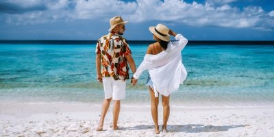 Žena a muž stojí na pláži a drží se za ruce.