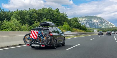 Auto s nosičem na kola na silnici, v pozadí hory