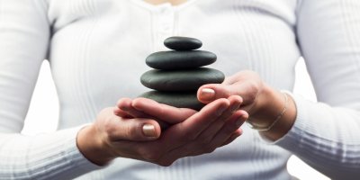 Žena drží v dlaních černé oblázky