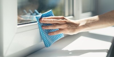 Žena utírá hadříkem plastové okno