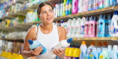 Žena se dvěma lahvemi v rukou v drogerii