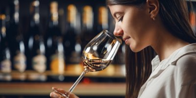 Žena čichá k bílému vínu ve sklenici