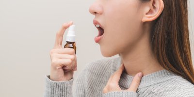 Žena si stříká sprej do krku