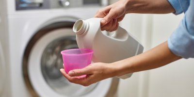 Žena nalévá do odměrky prací prostředek