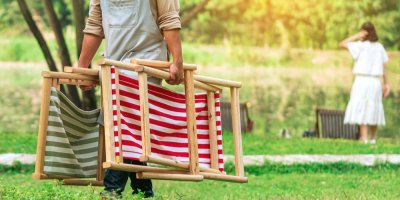 Muž odnáší ze zahrady dvě skládací lehátka