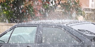 Kroupy dopadající na střechu černého auta